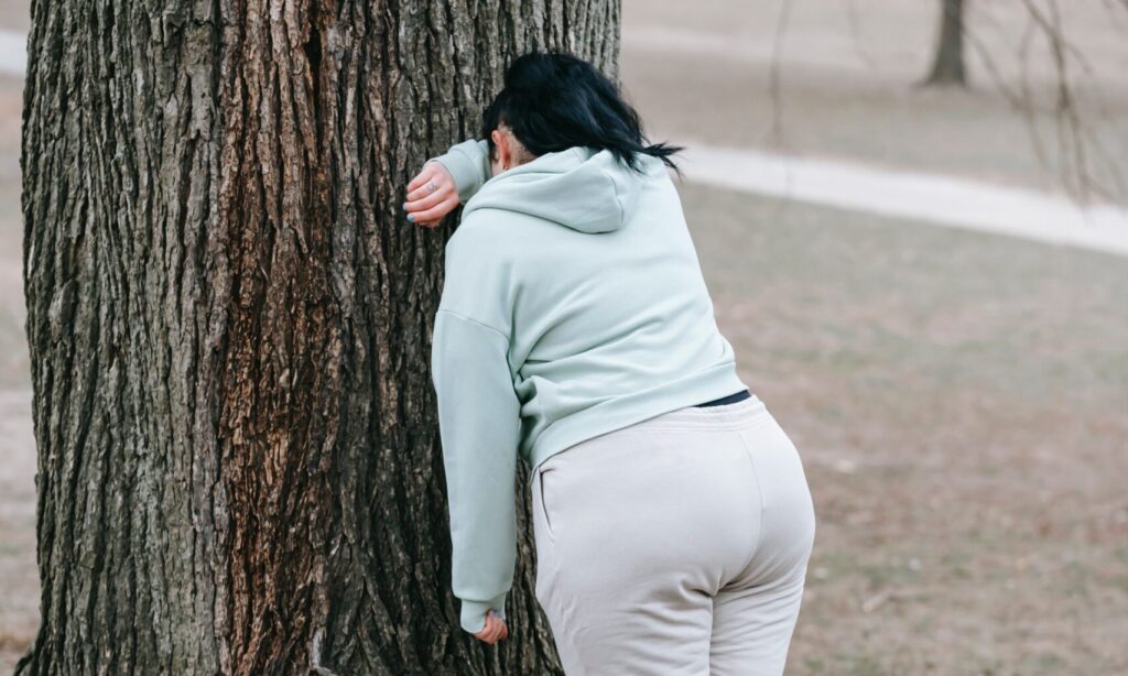 Upset woman leaning against a tree